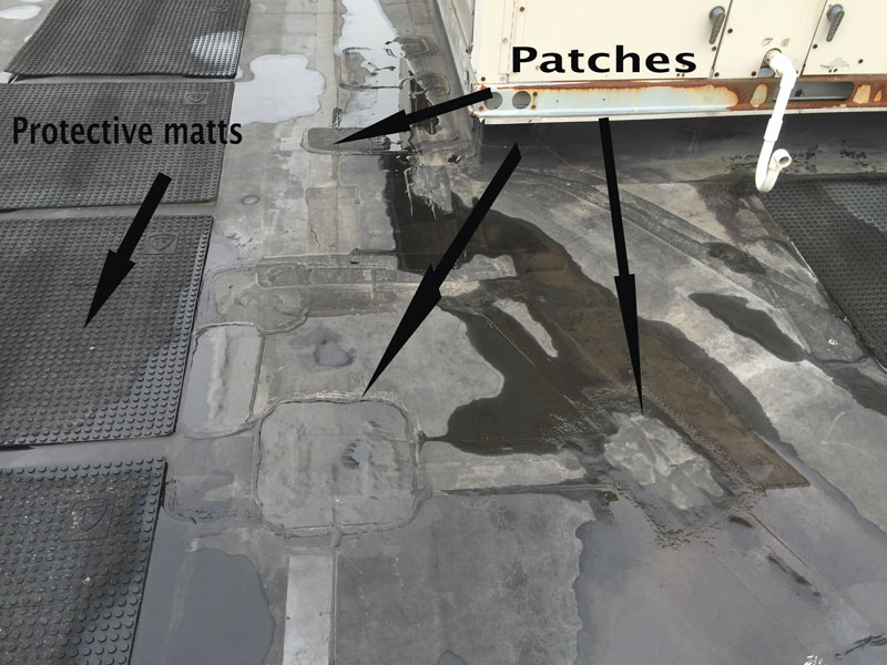 EPDM Roofing Problems - This image shows many repair patches where adhesives have failed due to harmful UV rays.